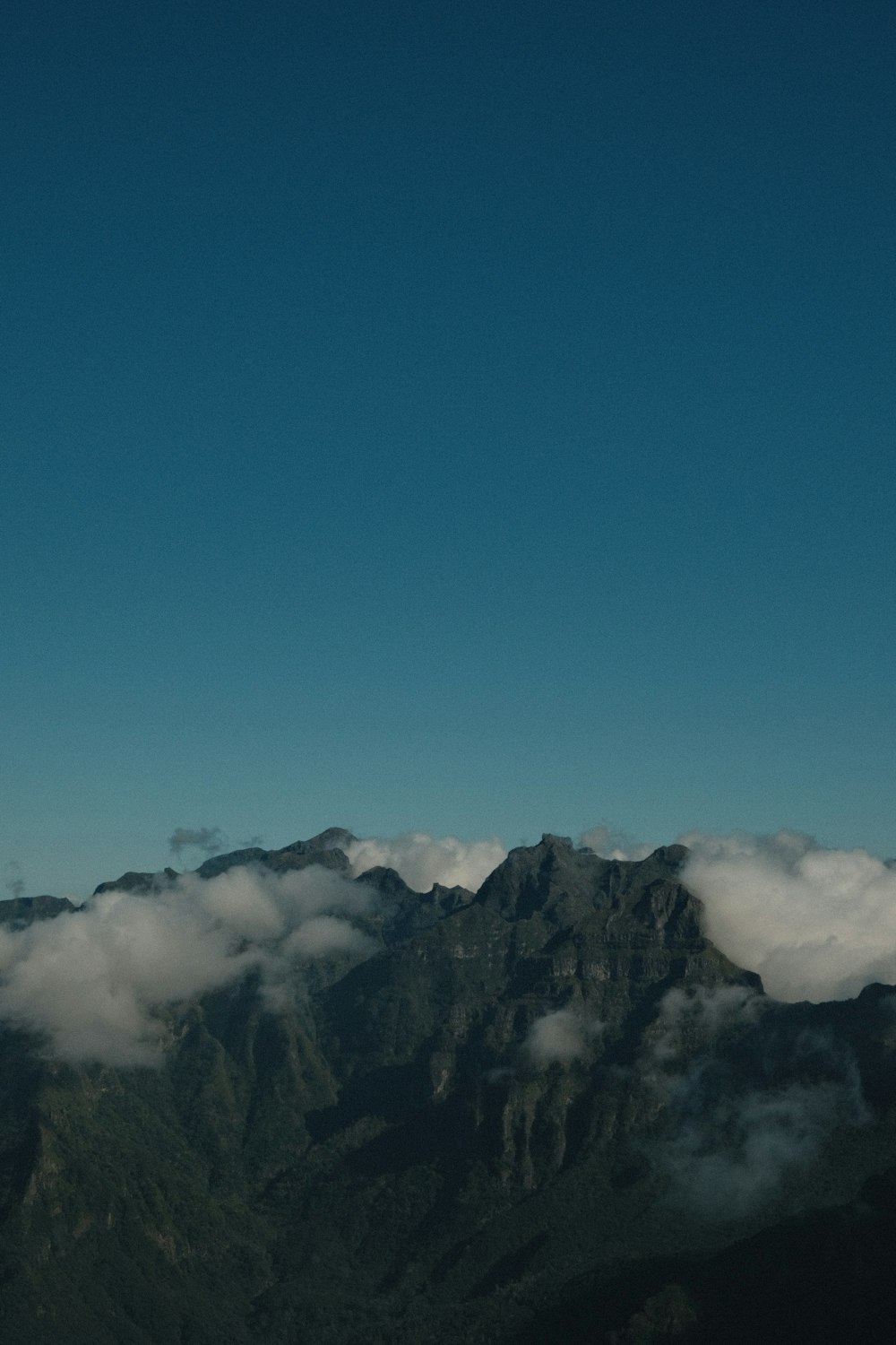 a plane flying over a mountain covered in clouds