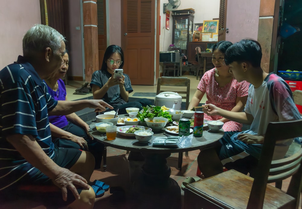 un grupo de personas sentadas alrededor de una mesa comiendo