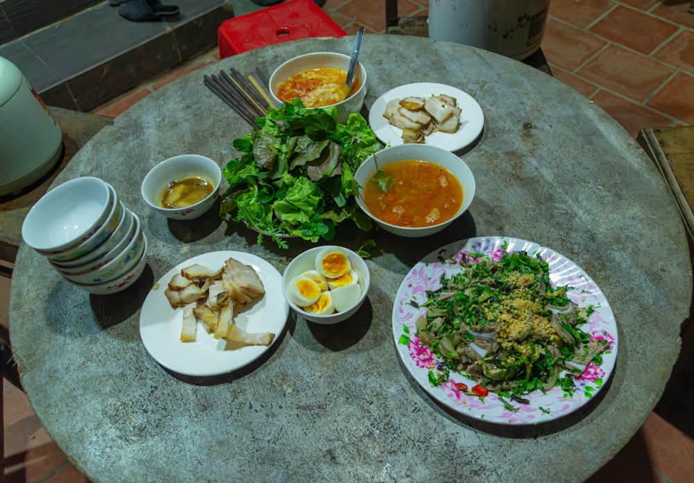 a table topped with plates of food and bowls of soup