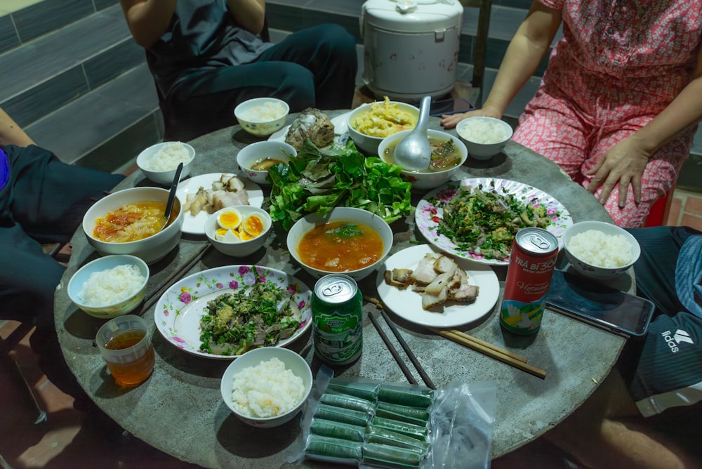 un grupo de personas sentadas alrededor de una mesa llena de comida