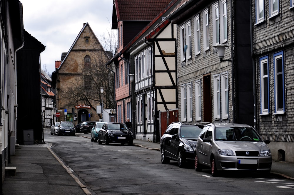 cars parked on the side of a street next to tall buildings