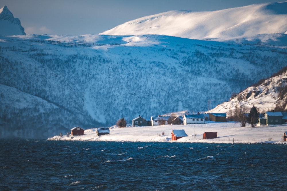 a snowy mountain with houses on the shore