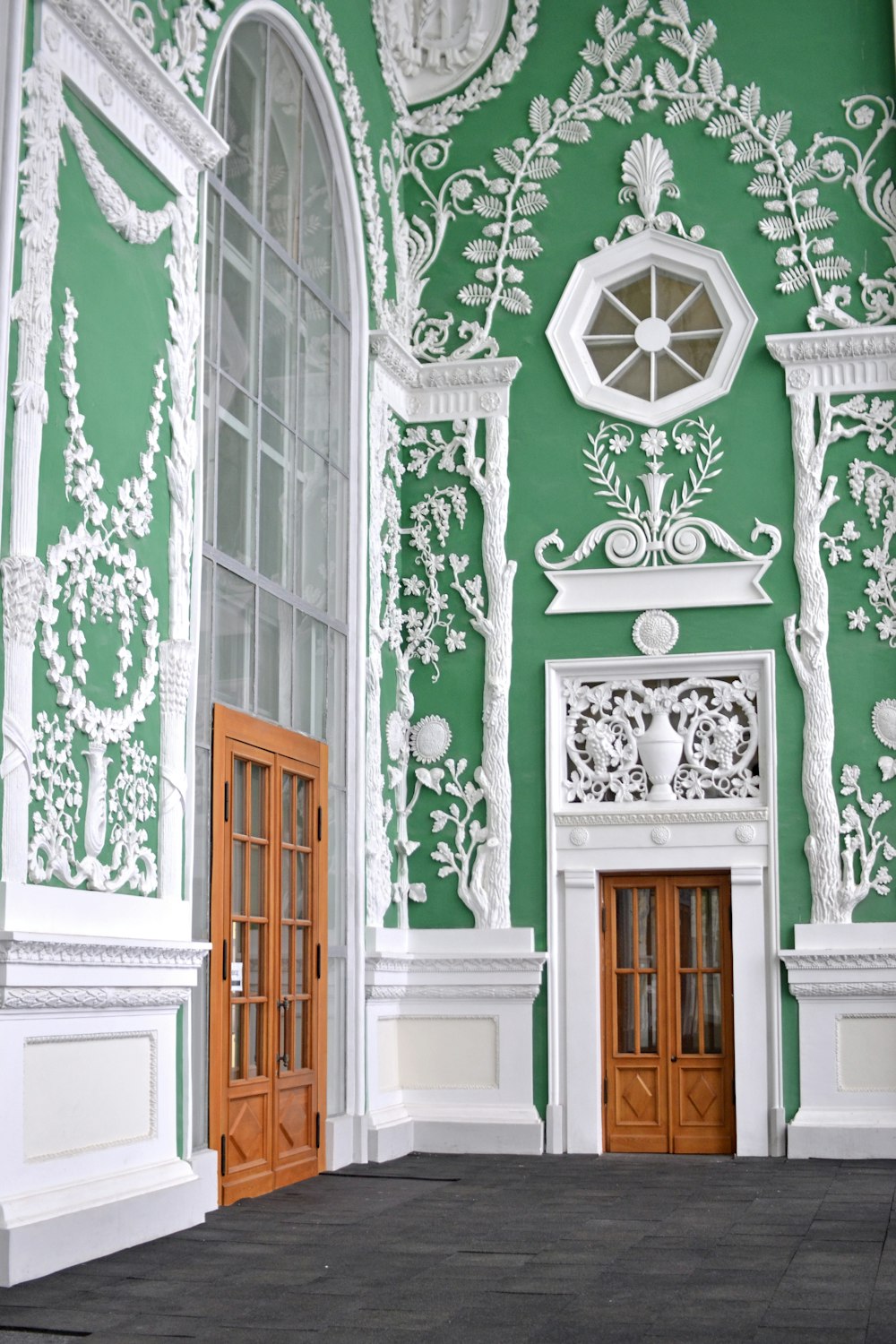 a green and white building with two wooden doors