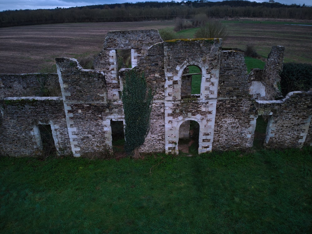 an aerial view of a stone building in the middle of a field