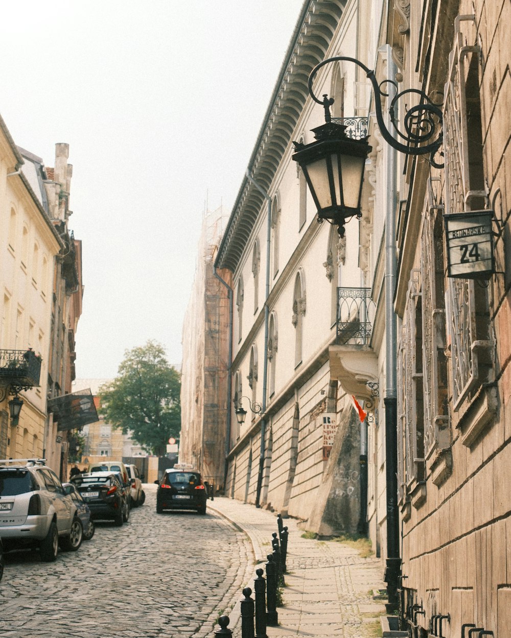 a cobblestone street lined with parked cars