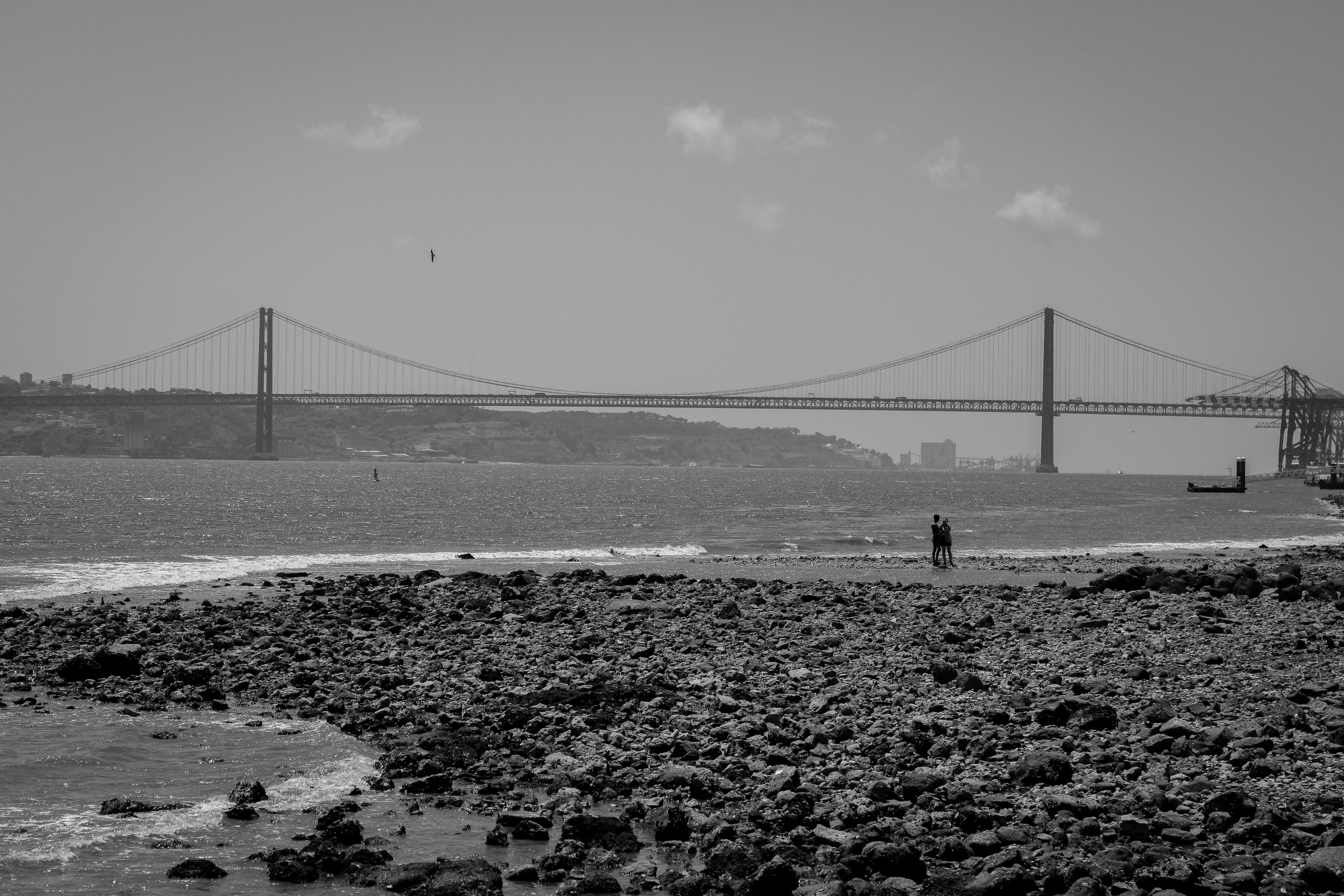 a black and white photo of a person walking on the beach, 