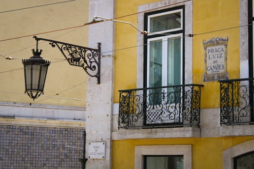 a yellow building with a black iron balcony