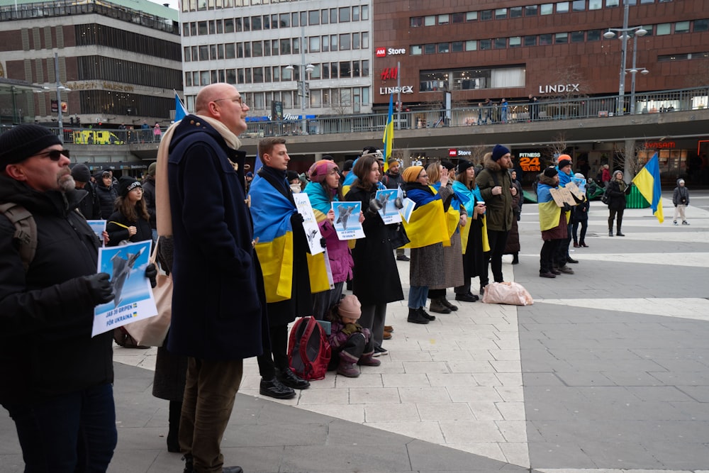 a group of people standing on a sidewalk holding signs