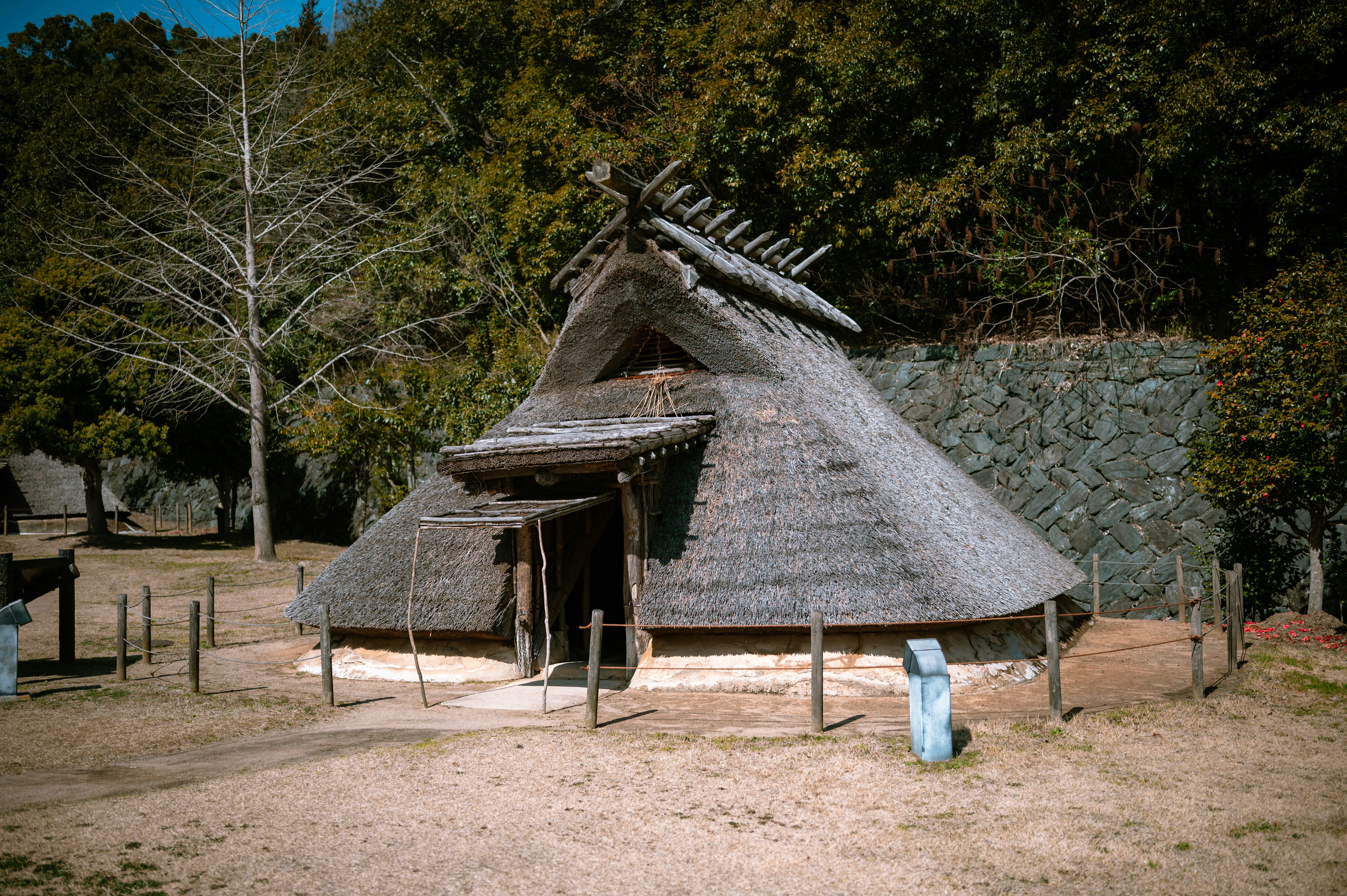 a hut with a thatched roof and a wooden fence