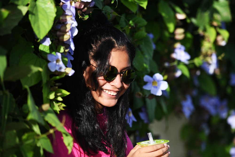 a woman in a pink shirt and sunglasses holding a drink