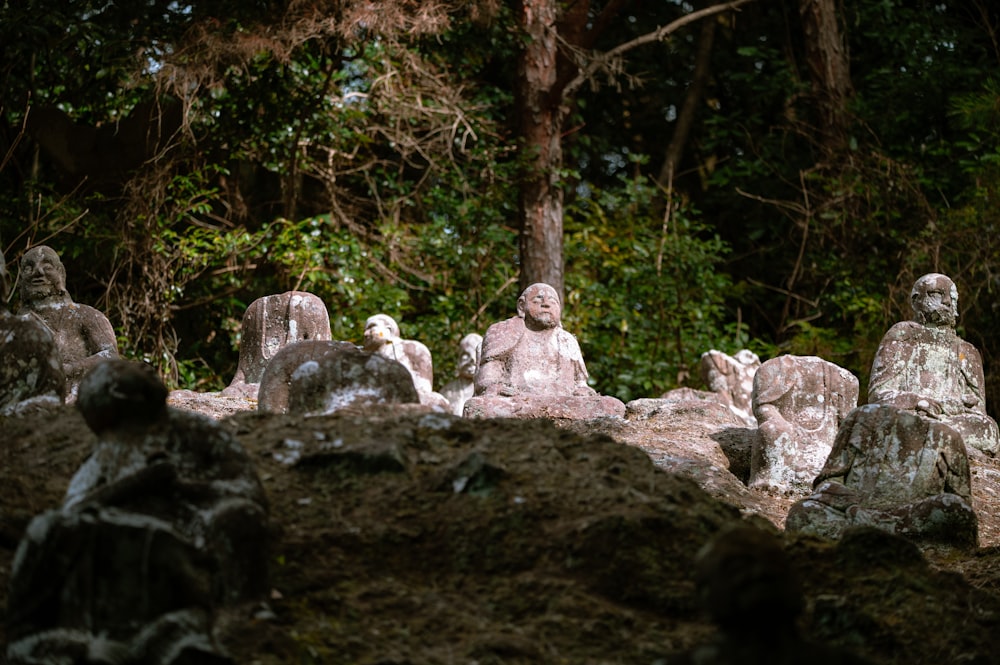 a group of statues sitting in the middle of a forest