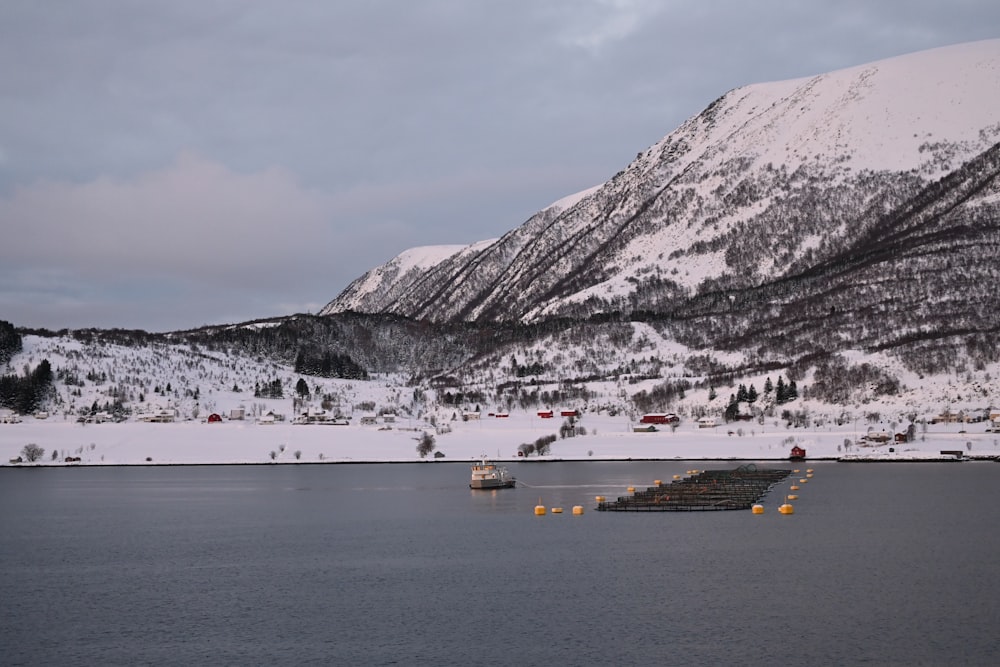 a mountain covered in snow next to a body of water