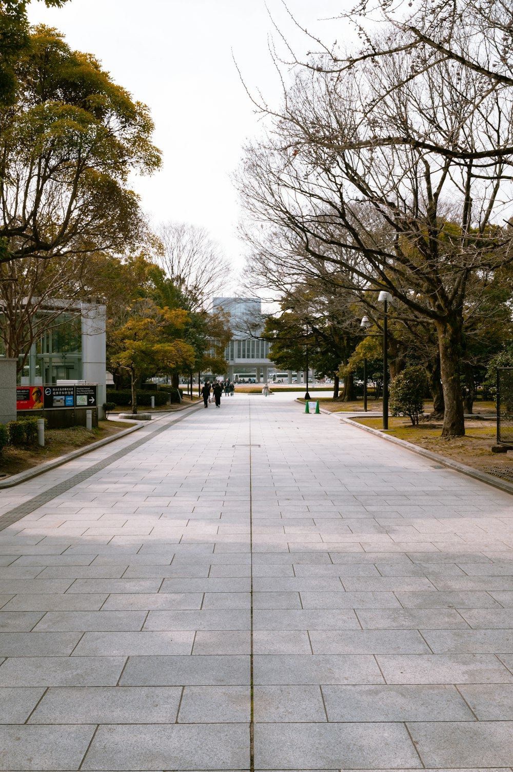 two people walking down a sidewalk in a park