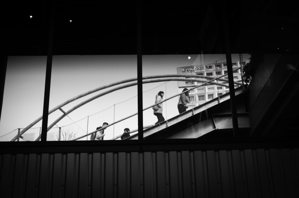 a black and white photo of people on a bridge