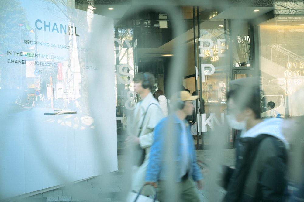 a blurry photo of people walking past a chanel store
