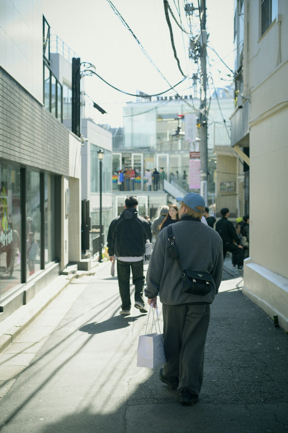 a group of people walking down a street next to tall buildings