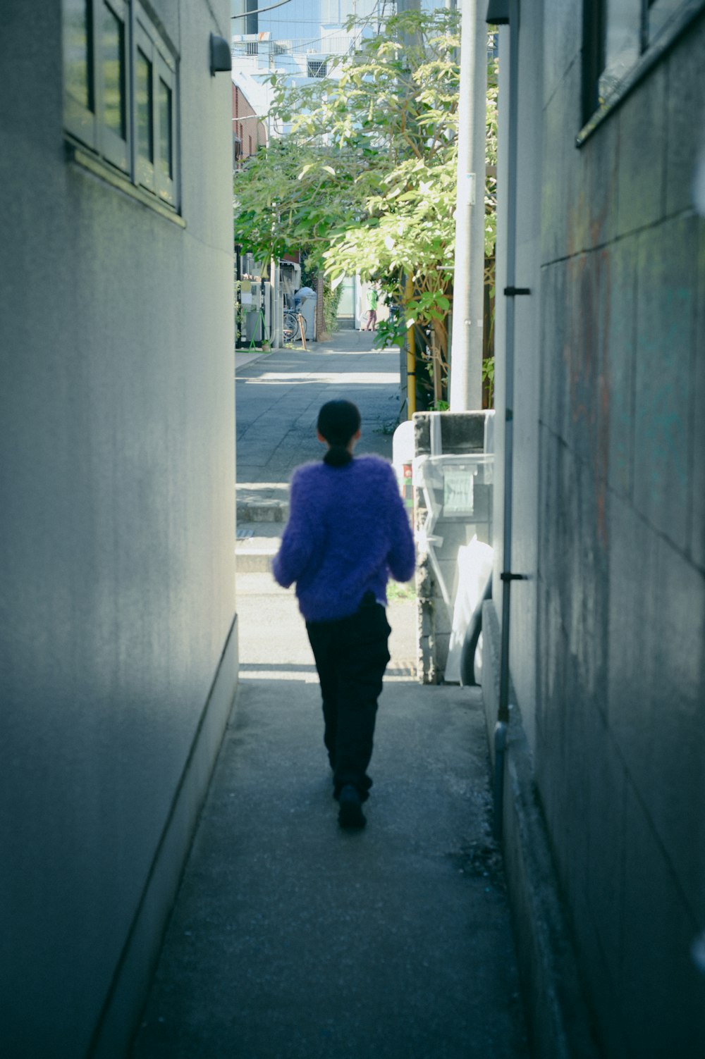 a woman walking down a narrow alley way