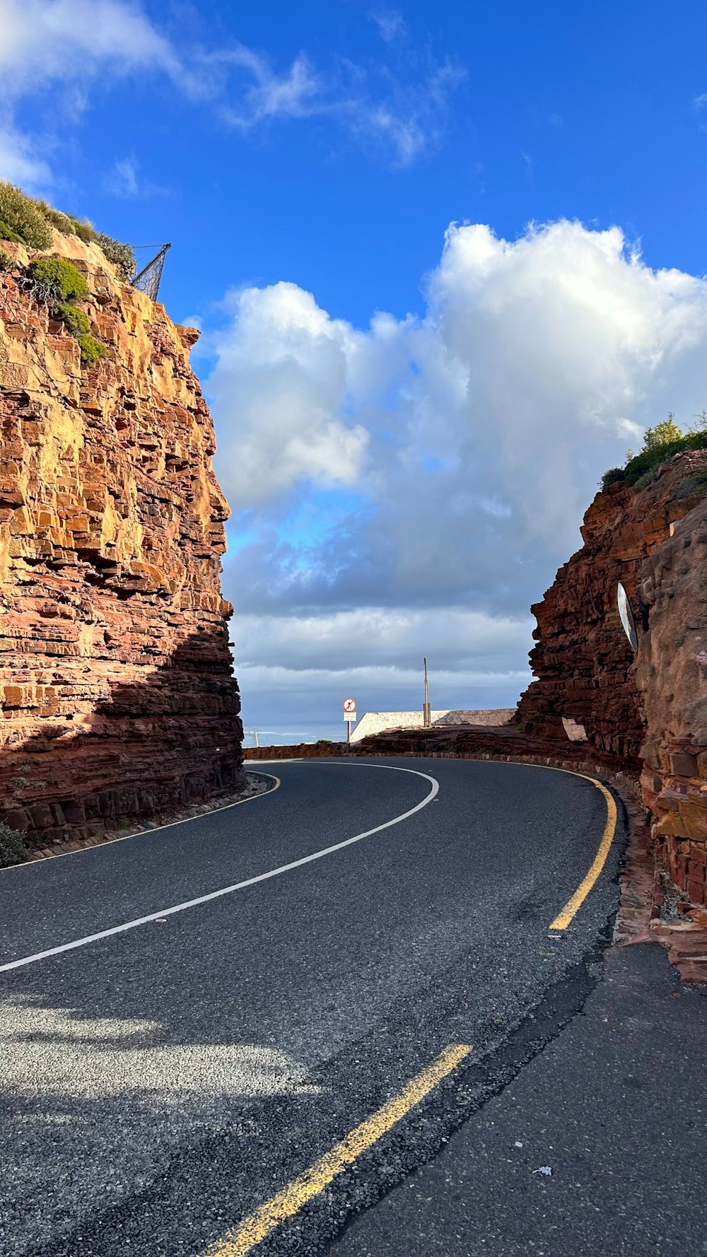 a curved road with a rock cliff in the background