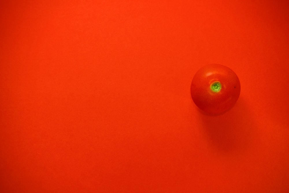 a tomato on a red surface with a green light
