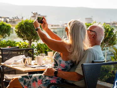a man and woman sitting at a table taking a picture