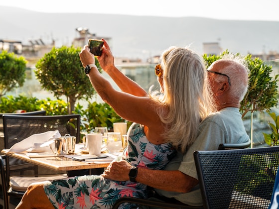 a man and woman sitting at a table taking a picture