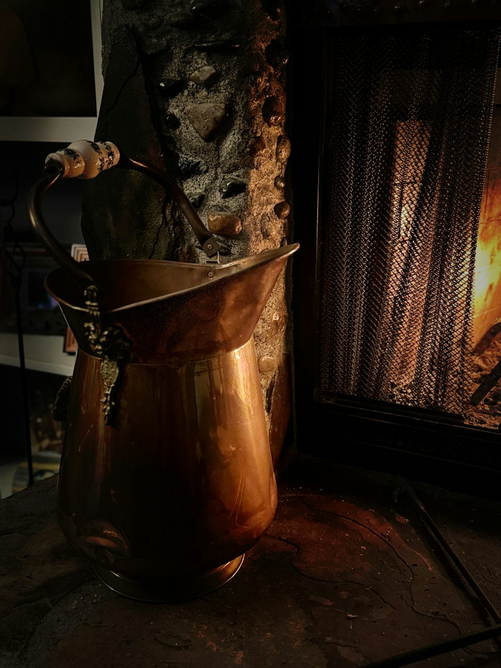 a copper pitcher sitting in front of a fireplace