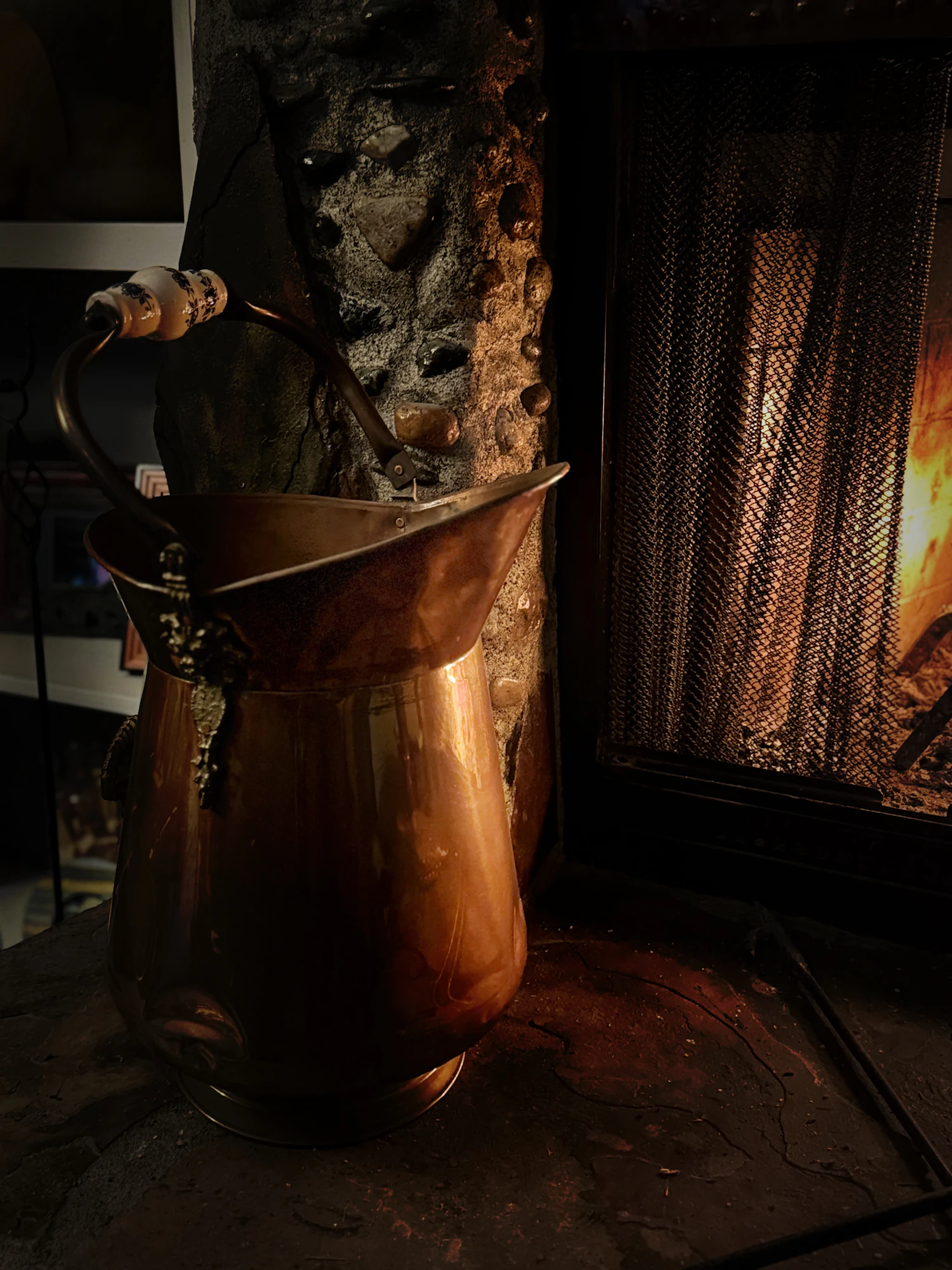 A copper vessel standing beside an open fire