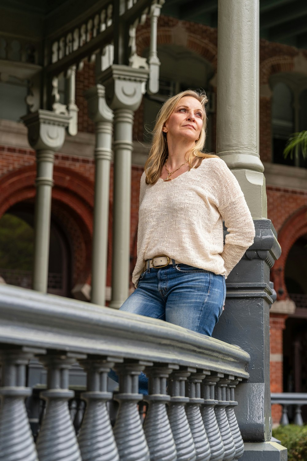 a woman leaning on a railing in front of a building