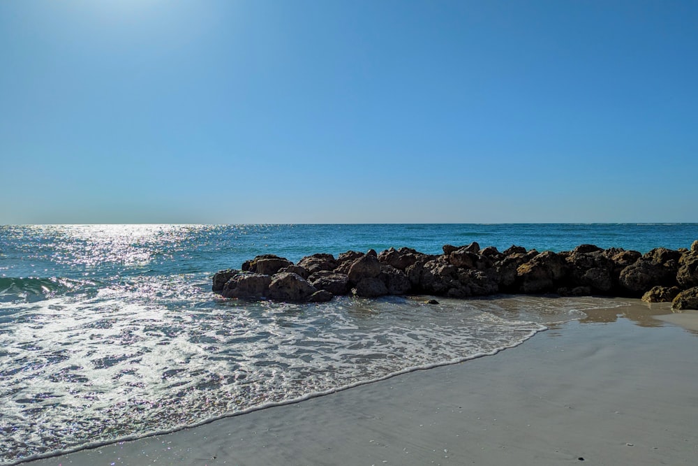uma praia com pedras e água em um dia ensolarado