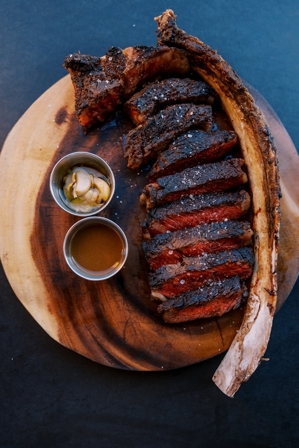 A wooden plate topped with ribs and sauce
