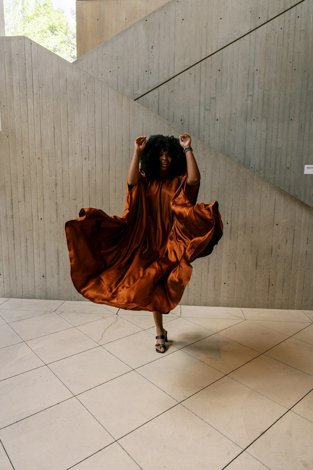 a woman in a brown dress is walking up a flight of stairs