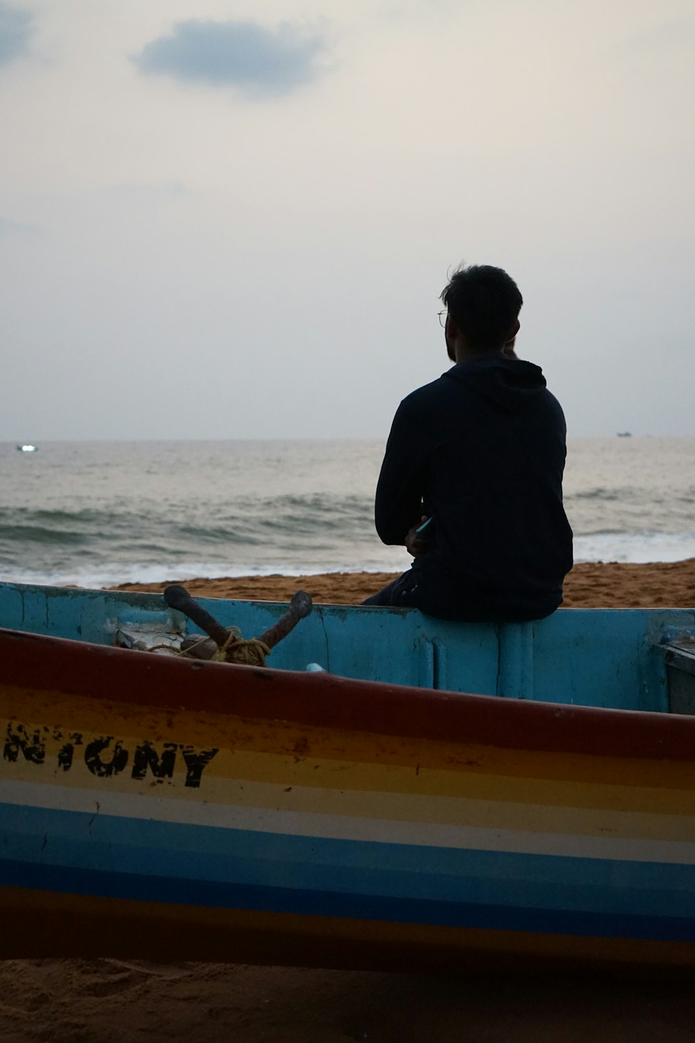 a man sitting in a boat on the beach