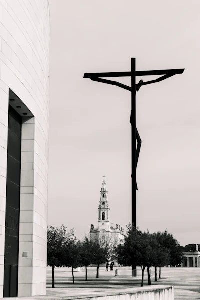a black and white photo of a cross and a building