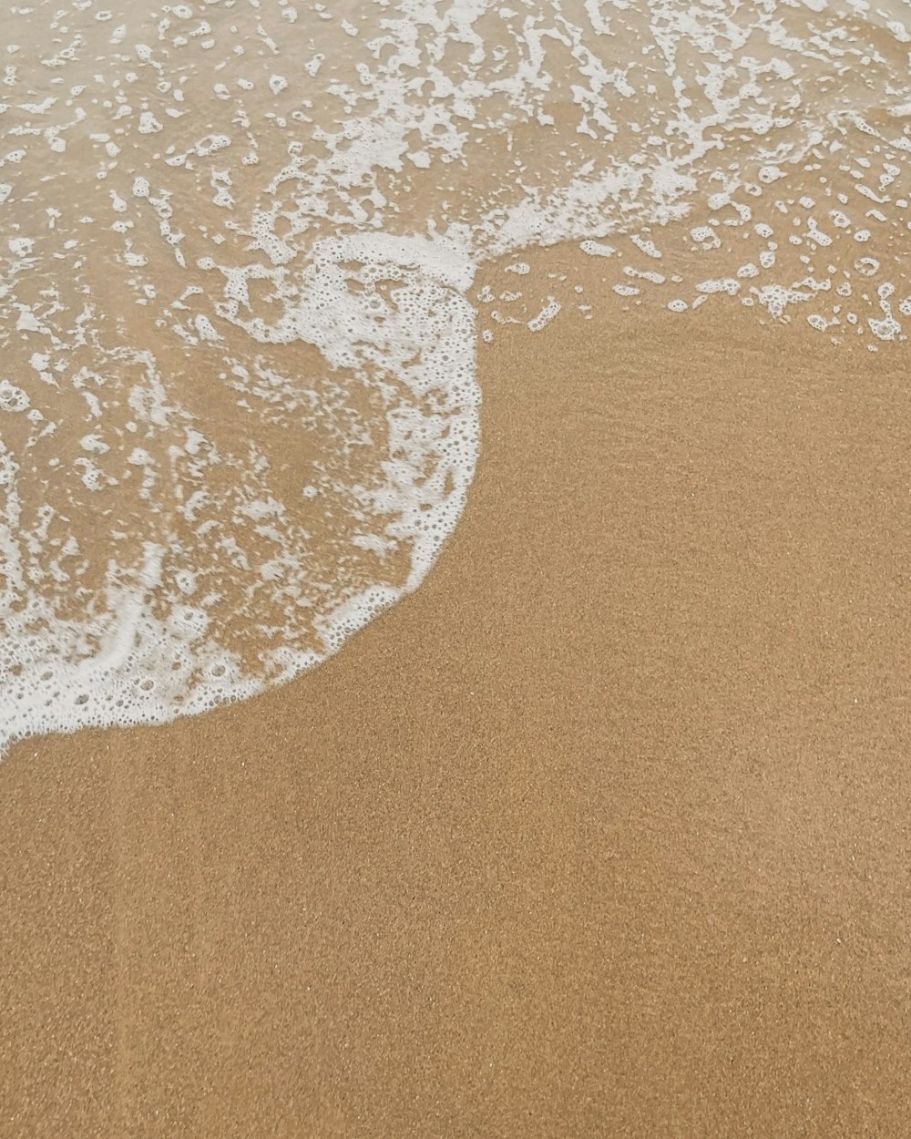 a person walking along the beach with a surfboard