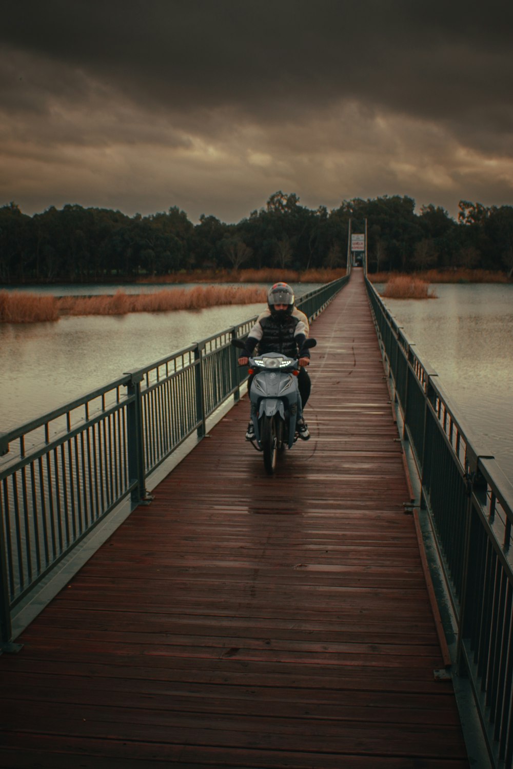 a man riding a motorcycle across a wooden bridge