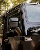 a black jeep parked in front of a tree
