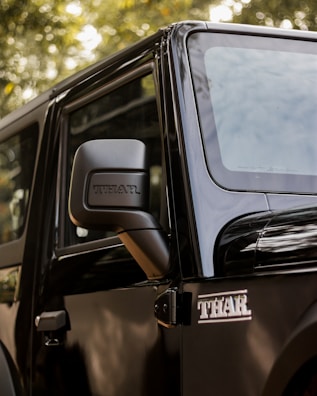 a black jeep parked in front of a tree