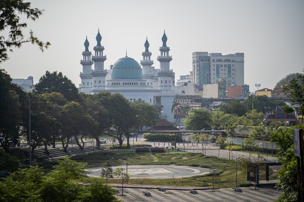 a large white building with a blue dome in the middle of a park