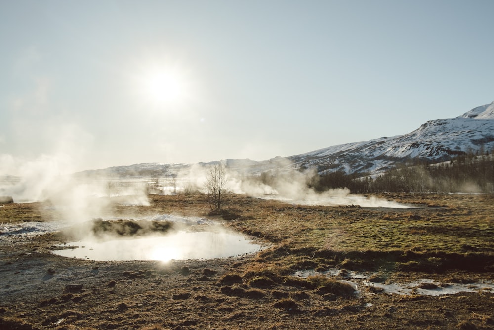 a small pond of water surrounded by snow covered mountains