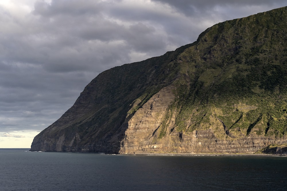 a large mountain sitting on the side of a body of water