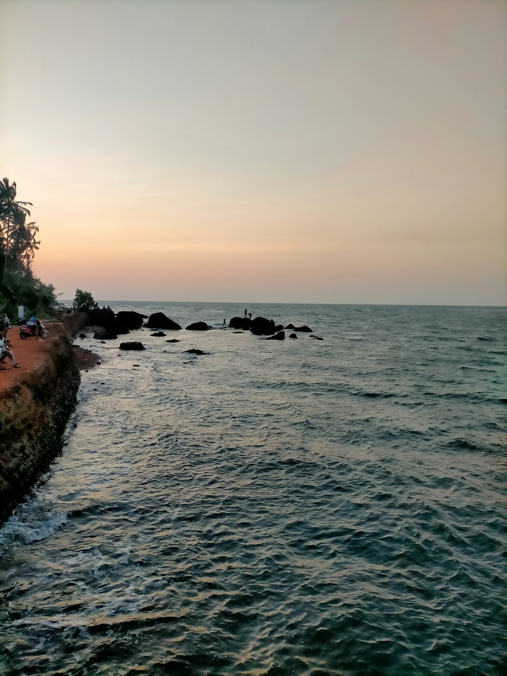 a couple of people sitting on a bench next to the ocean