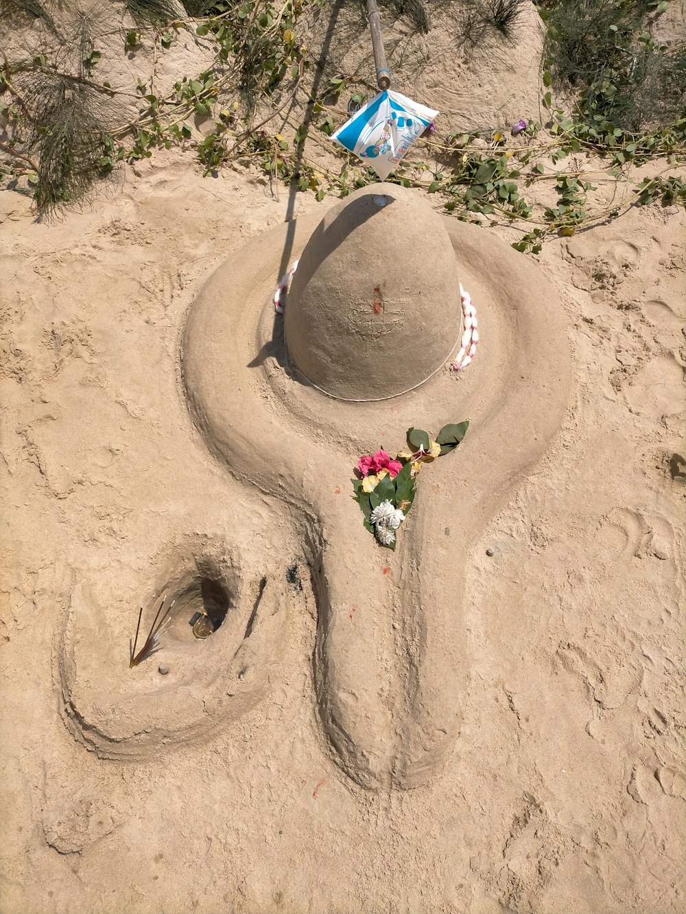a sand sculpture with flowers and a street sign