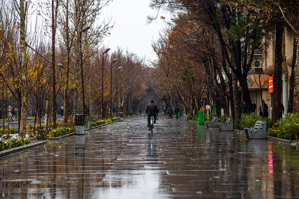 a man riding a bike down a rain soaked street