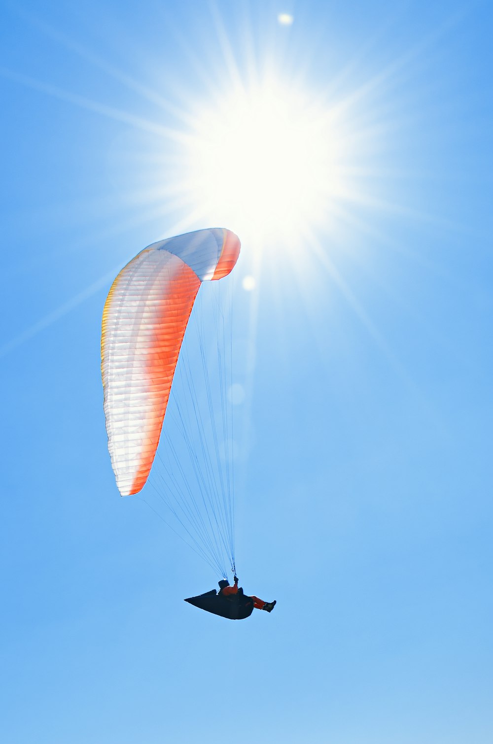 une personne qui fait du parachute ascensionnel au soleil par temps clair