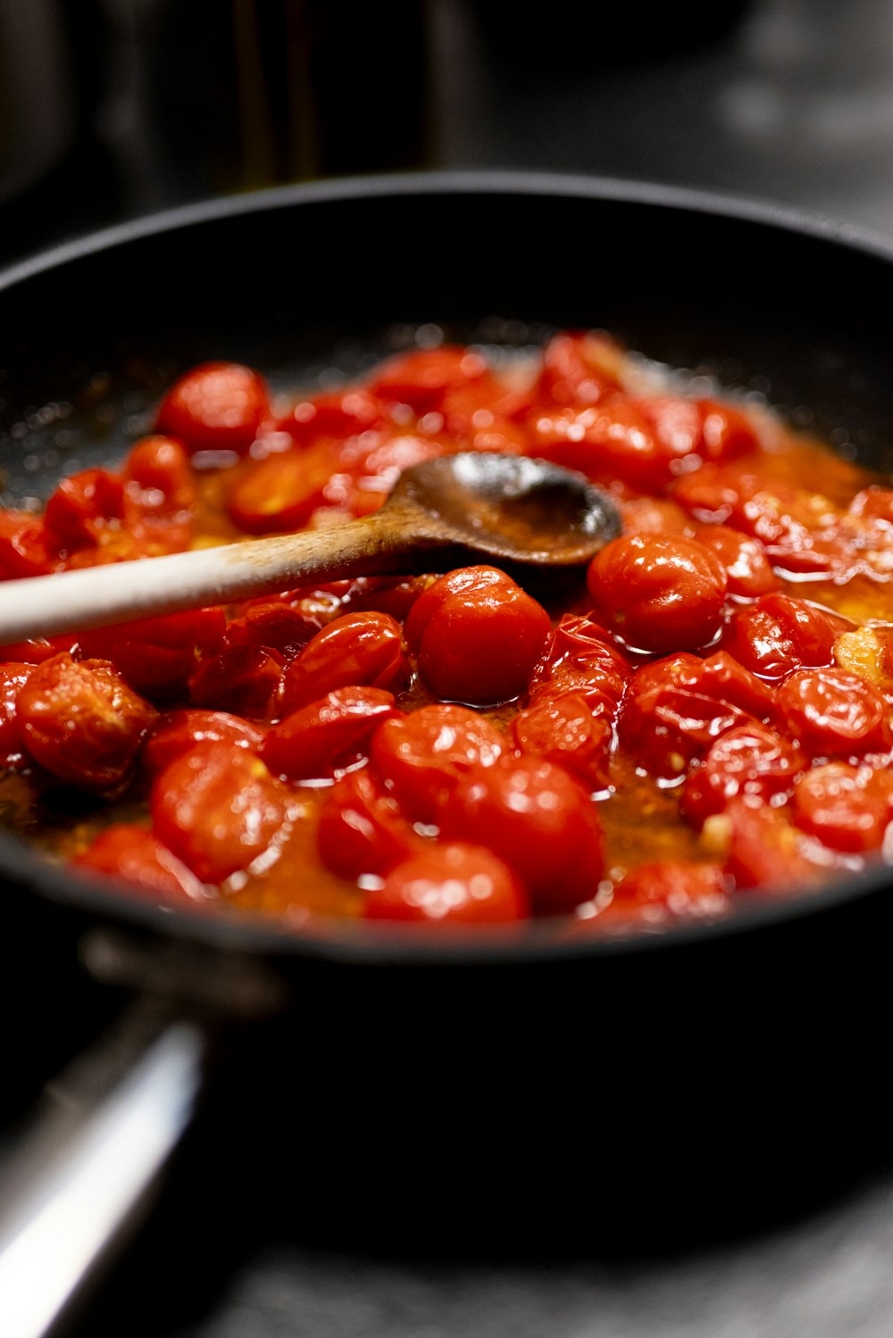 a pan filled with tomatoes and a wooden spoon