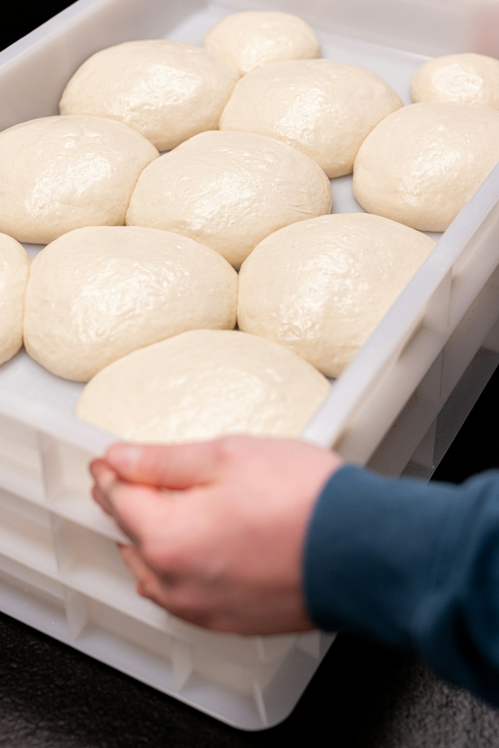 a person holding a plastic container filled with dough