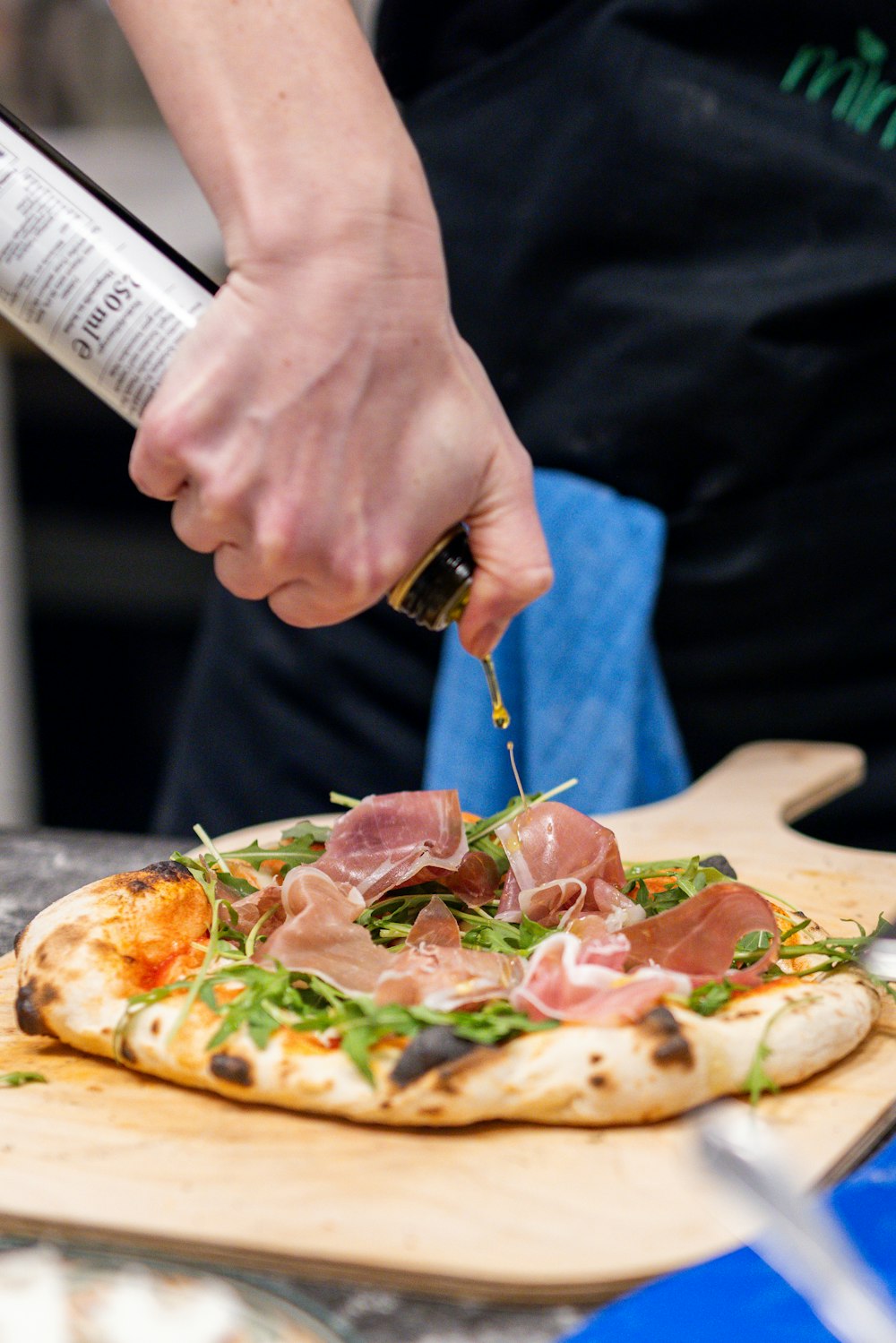 a person cutting a pizza on top of a wooden cutting board