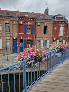 a blue railing with flowers on it next to a body of water