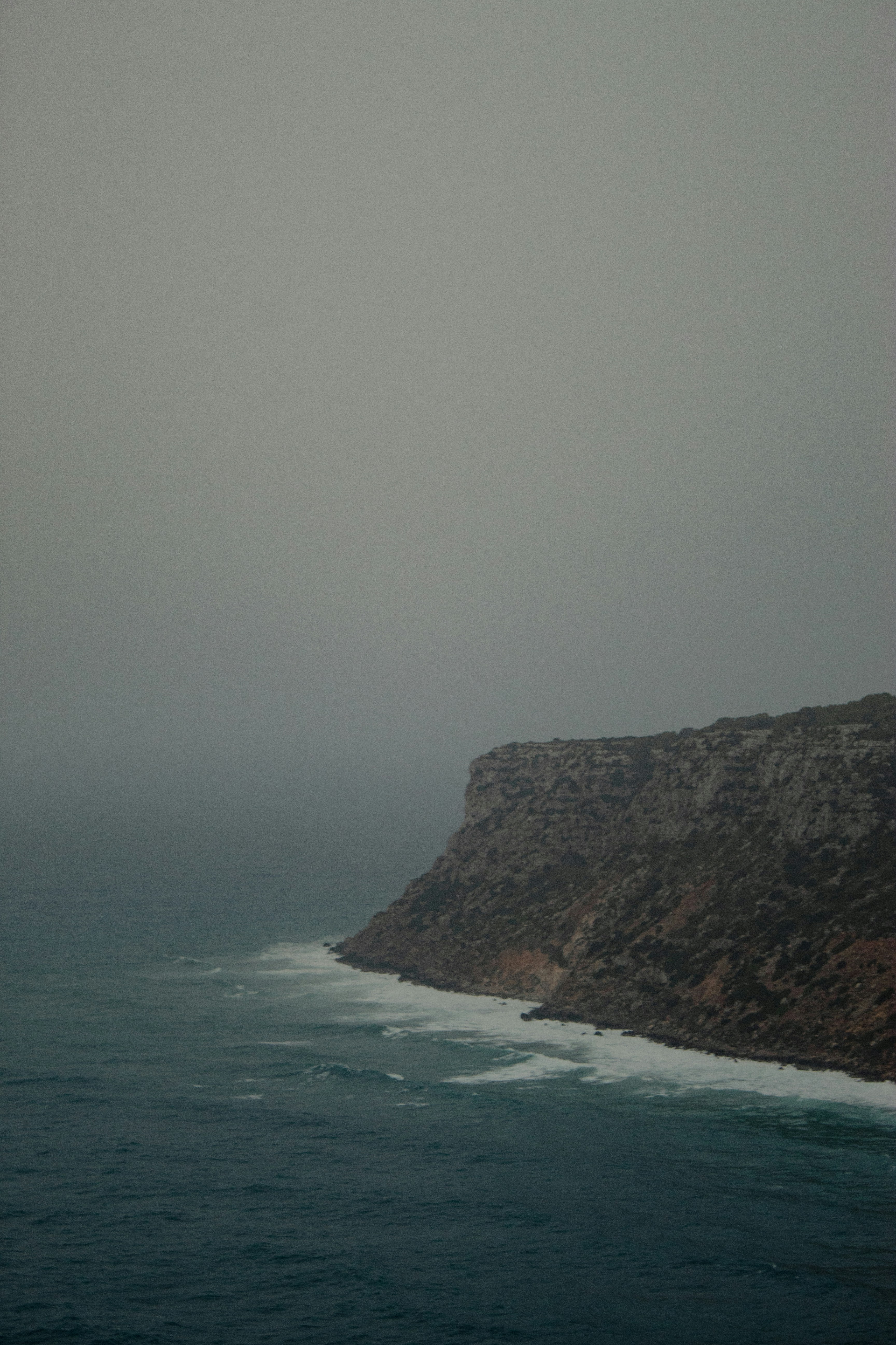 an airplane flying over the ocean on a foggy day