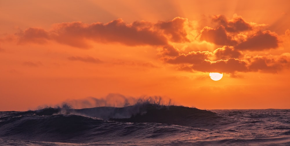 the sun is setting over the ocean waves